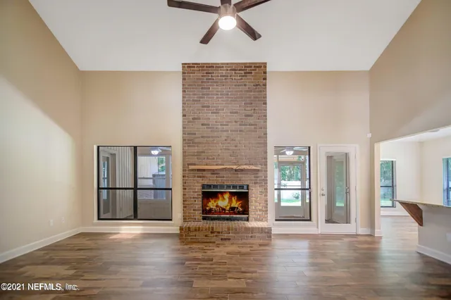 a view of an empty room with wooden floor fireplace and a window