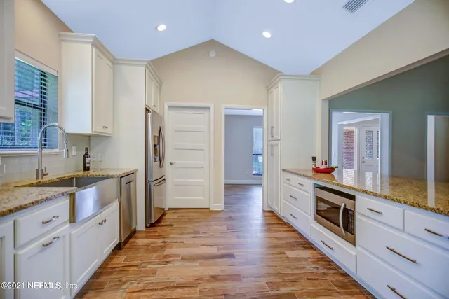 a large kitchen with stainless steel appliances wooden cabinets and a wooden floor