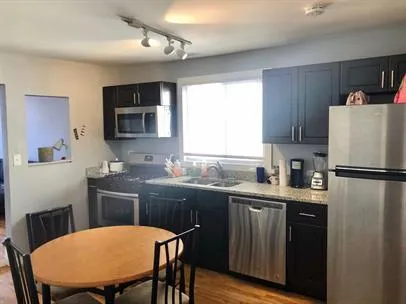 a kitchen with a table chairs refrigerator and microwave