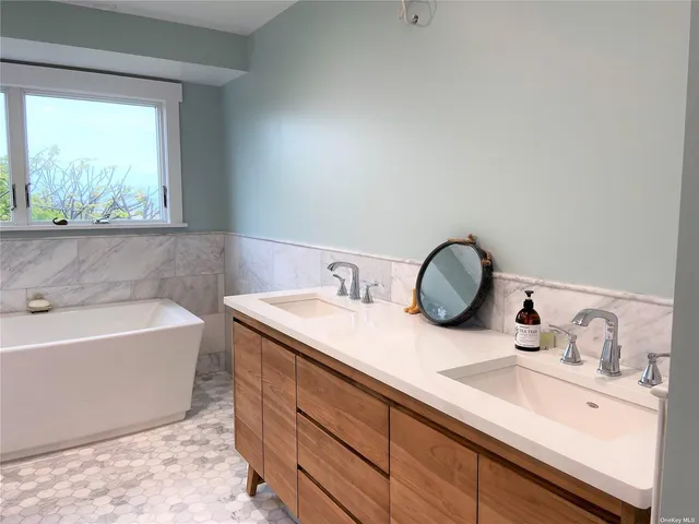 a bathroom with a granite countertop sink and a bathtub