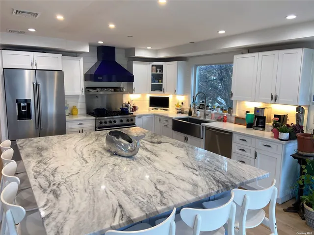 a kitchen with stainless steel appliances kitchen island granite countertop a sink a stove a refrigerator cabinets and a dining table