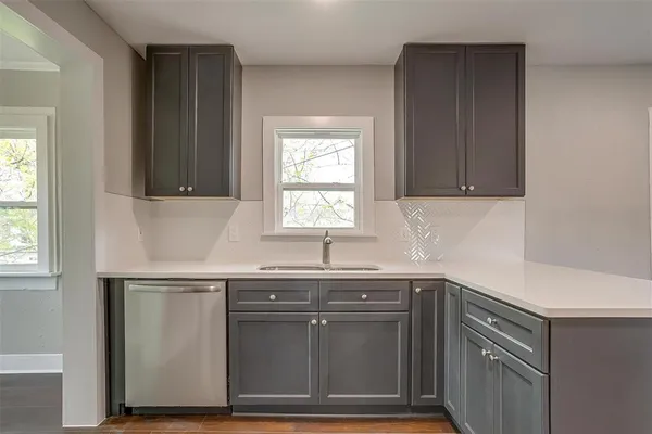 a kitchen with granite countertop a sink dishwasher a stove and cabinets
