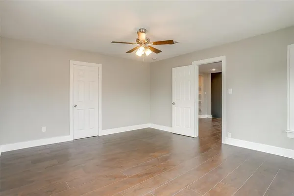 an empty room with wooden floor ceiling fan and window