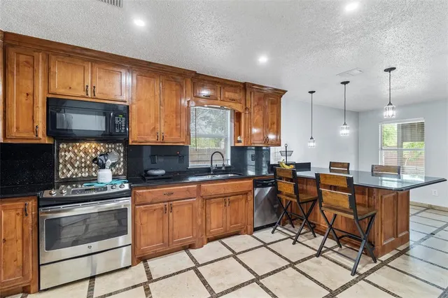 a kitchen with stainless steel appliances kitchen island granite countertop a stove top oven a sink dishwasher a dining table and chairs with wooden floor