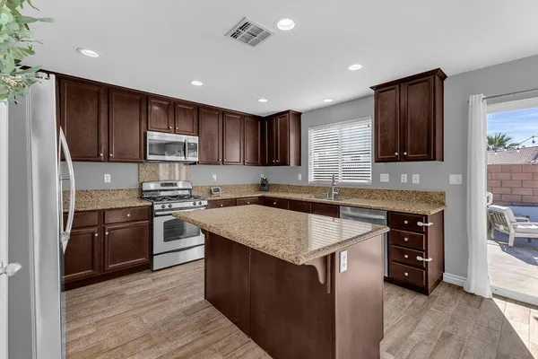 a kitchen with kitchen island granite countertop a stove sink cabinets and refrigerator