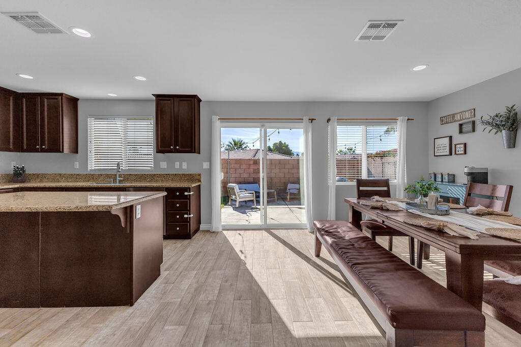 84285 Tramonto Way Indio, CA 92203 - Photo 13 of 63 a large kitchen with stainless steel appliances a stove a sink dishwasher a microwave oven and a dining table with wooden floor