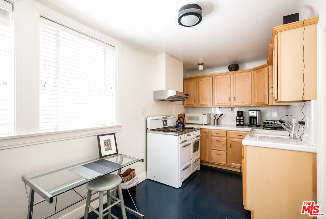 239 West Channel Road Santa Monica, CA 90402 - Photo 27 of 30 a kitchen with a stove a sink white cabinetry and wooden floor