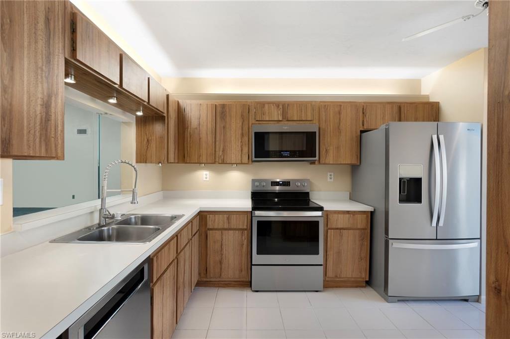 1814 Kings Lake Boulevard, Unit 201 Naples, FL 34112 - Photo 5 of 18 a kitchen with stainless steel appliances a stove sink microwave and refrigerator