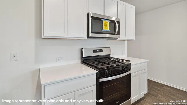 a kitchen with stainless steel appliances granite countertop white cabinets a stove top oven