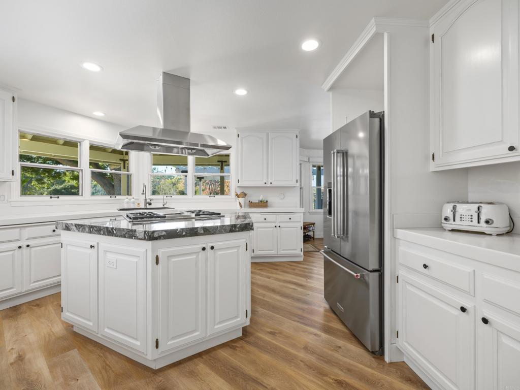 9 Country Glen Road Fallbrook, CA 92028 - Photo 8 of 74 a kitchen with granite countertop a refrigerator a sink and white cabinets