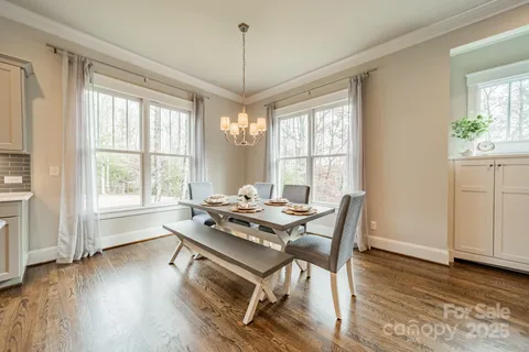 a dining room with wooden floor a chandelier a glass table and chairs