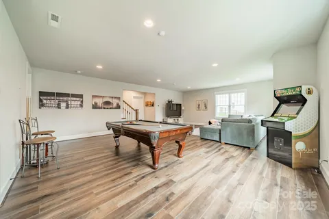 a room with furniture pool table wooden floor and windows