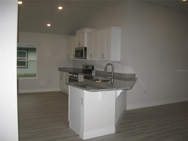 a kitchen with stainless steel appliances granite countertop a sink stove and cabinets