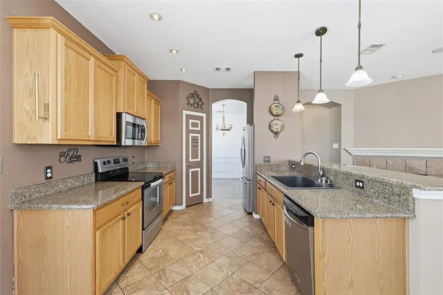 a large kitchen with a sink and dishwasher a stove top oven with wooden floor