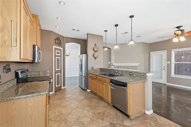 a kitchen with granite countertop a sink a counter top space and stainless steel appliances
