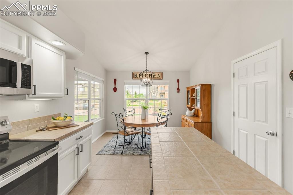 10467 Pictured Rocks Drive Peyton, CO 80831 - Photo 12 of 47 a kitchen with a table chairs refrigerator and cabinets