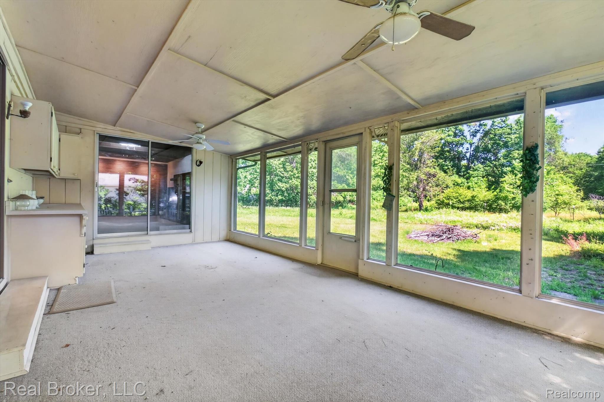 48050 Hull Road Belleville, MI 48111 - Photo 18 of 39 Enclosed porch featuring multiple large windows, two ceiling fans with integrated lighting, built-in cabinetry, and a sliding glass door