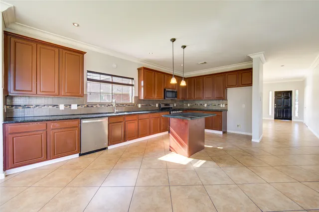 a large kitchen with granite countertop a stove a sink a counter space and cabinets