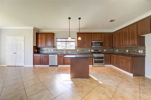 a large kitchen with granite countertop a stove a sink a counter top space and cabinets