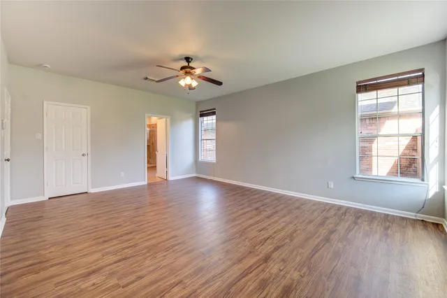 a view of an empty room with a window and wooden floor