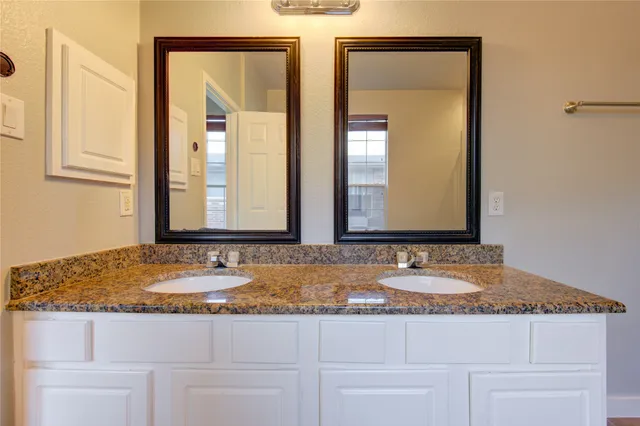 a bathroom with mirror granite countertop sink and a mirror