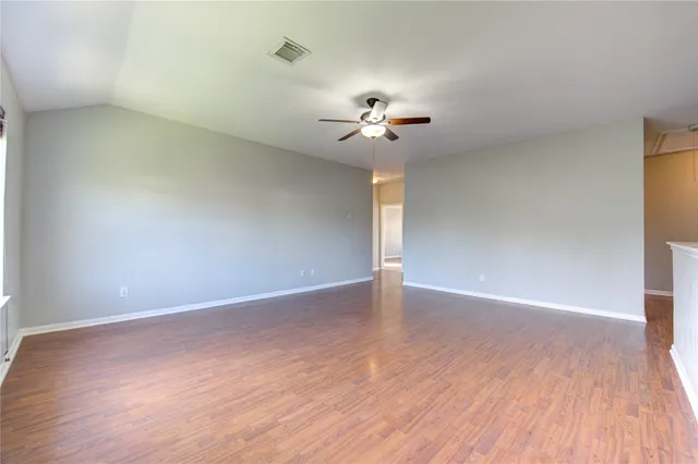 a view of an empty room with a chandelier fan and wooden floor