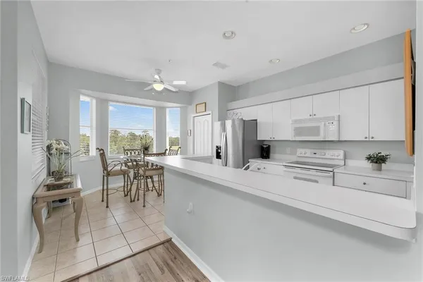 a kitchen with white cabinets and dining table