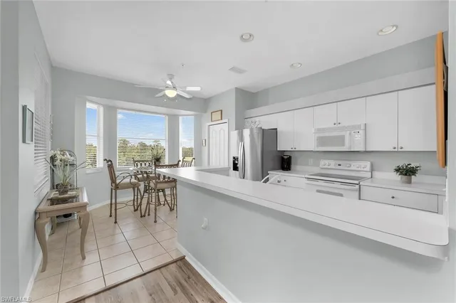 a kitchen with white cabinets and dining table