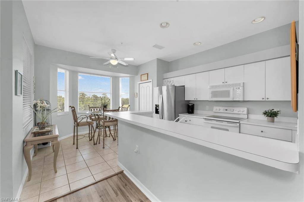 3800 Sawgrass Way, Unit 3142 Naples, FL 34112 - Photo 11 of 50 a kitchen with white cabinets and dining table