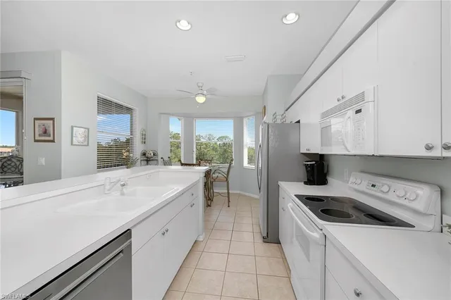a kitchen with a sink a stove a refrigerator and white cabinets