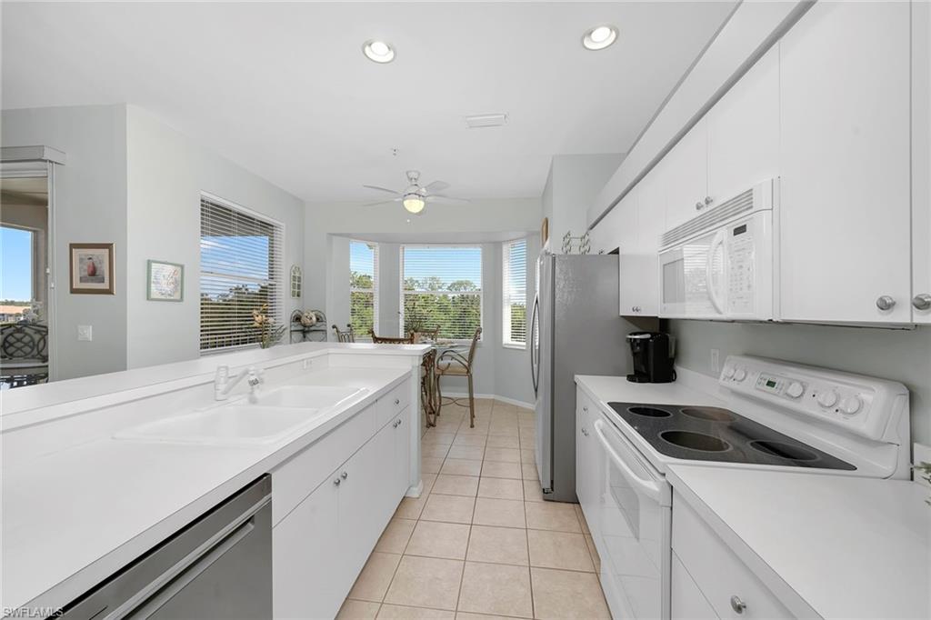 3800 Sawgrass Way, Unit 3142 Naples, FL 34112 - Photo 13 of 50 a kitchen with a sink a stove a refrigerator and white cabinets