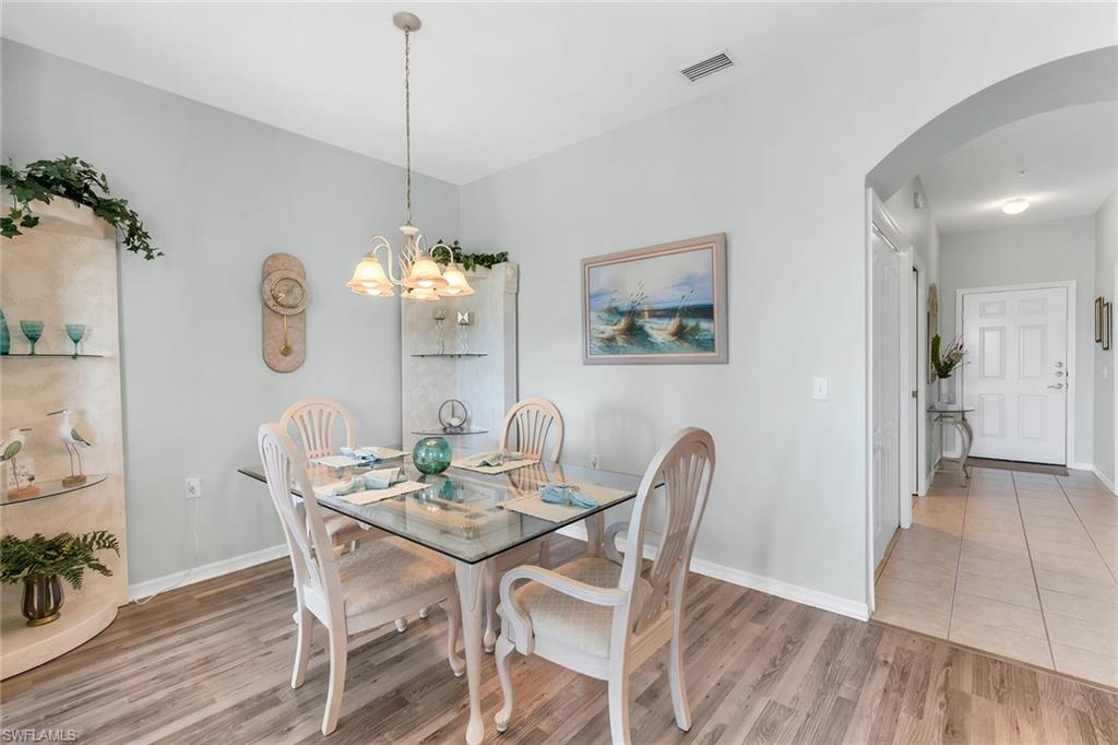 3800 Sawgrass Way, Unit 3142 Naples, FL 34112 - Photo 18 of 50 a view of a dining room with furniture a chandelier and wooden floor