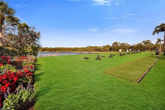 a view of a patio with chairs and table under an umbrella with a barbeque