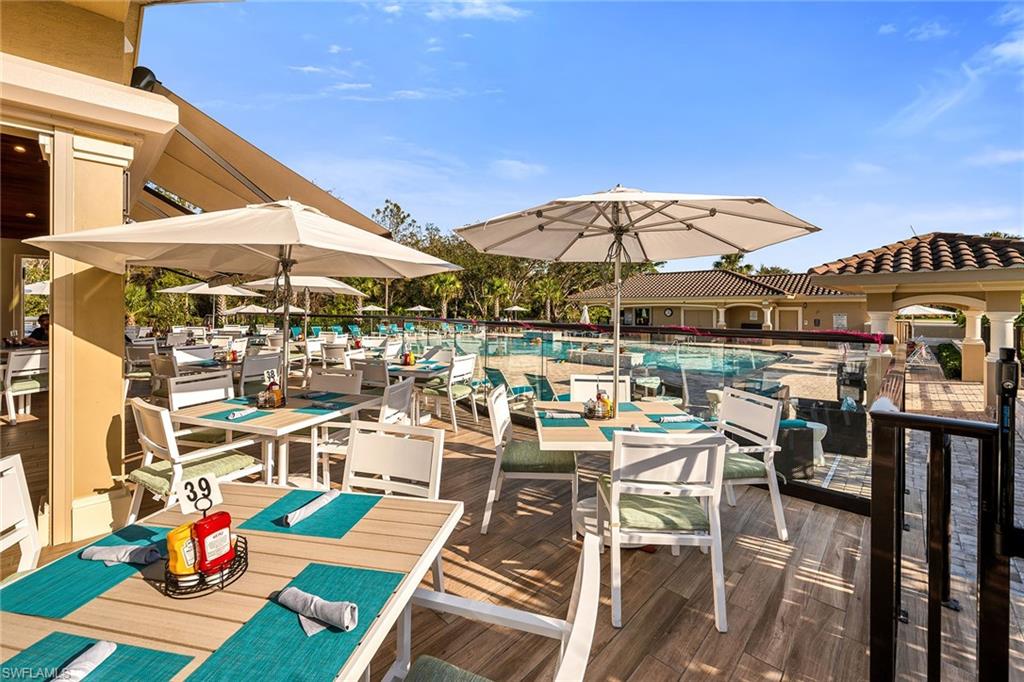 3800 Sawgrass Way, Unit 3142 Naples, FL 34112 - Photo 36 of 50 a view of a patio with chairs and table under an umbrella with a barbeque