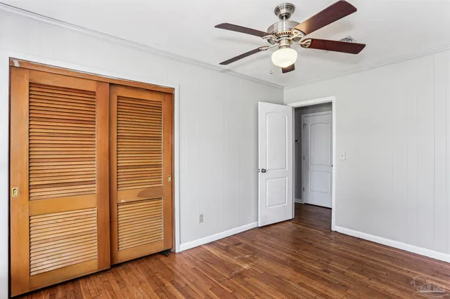 an empty room with wooden floor chandelier fan and windows