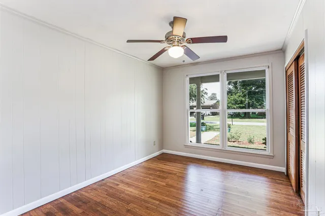 an empty room with wooden floor fan and windows