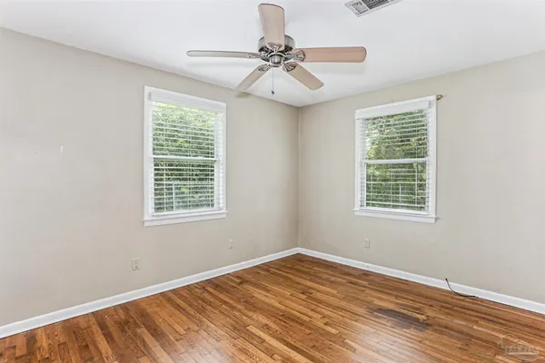 a view of empty room with wooden floor and fan