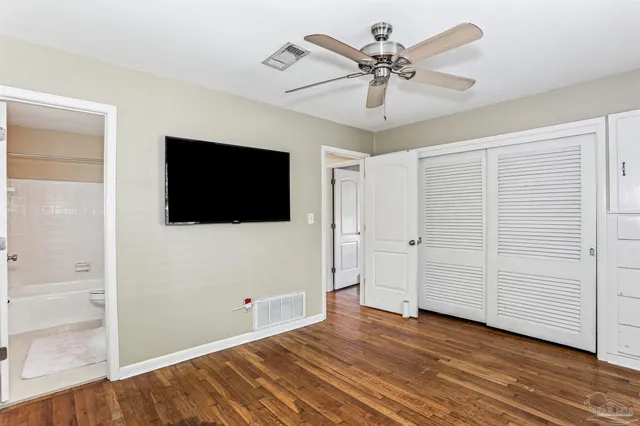 a view of a livingroom with an empty space a ceiling fan and wooden floor