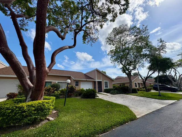 a front view of a house with a garden and tree