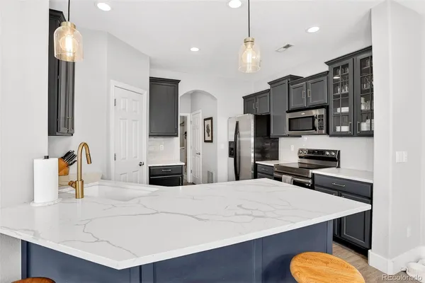 a large kitchen with stainless steel appliances a refrigerator a sink dishwasher a oven with white cabinets and countertops