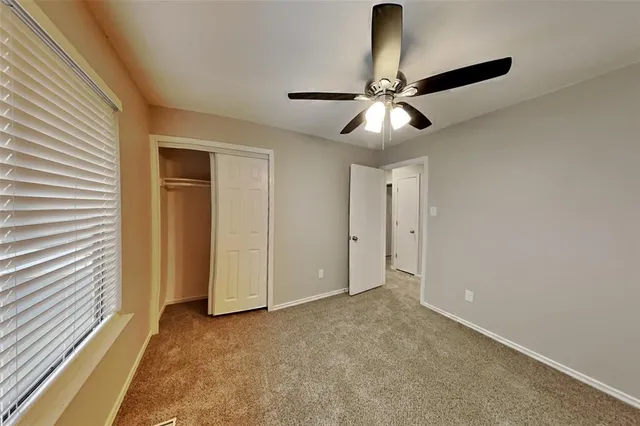 a view of an empty room and chandelier fan