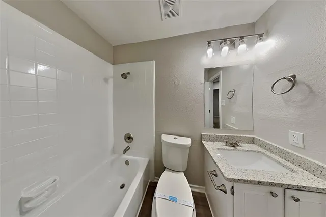 a bathroom with a granite countertop sink a toilet and shower
