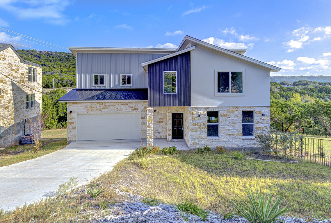 18414 Roundrock Road Jonestown, TX 78645 - Photo 1 of 30 Modern home with a standing seam roof, a metal roof, a garage, stone siding, and driveway