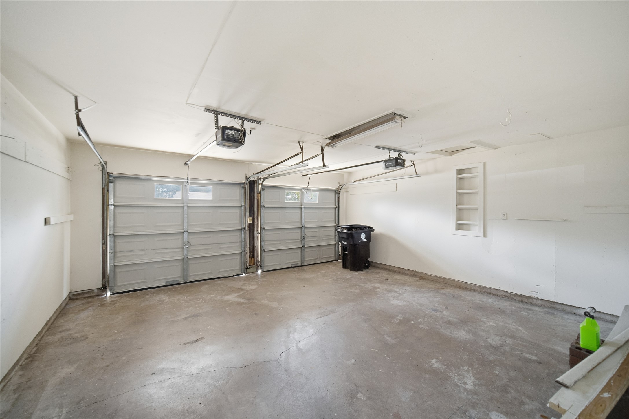 9524 Truscon Drive Houston, TX 77080 - Photo 22 of 30 Spacious two-car garage with concrete flooring and dual overhead doors. The garage is clean and well-lit, offering ample room for vehicles and additional storage needs.