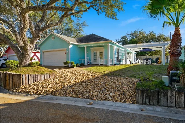 a front view of a house with a garden and tree