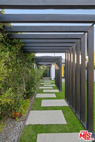 a view of a pathway of a house with plants and big trees