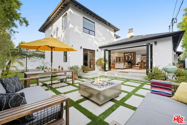 a view of a patio with couches table and chairs under an umbrella