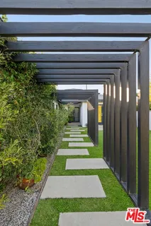 a view of a pathway of a house with plants and big trees