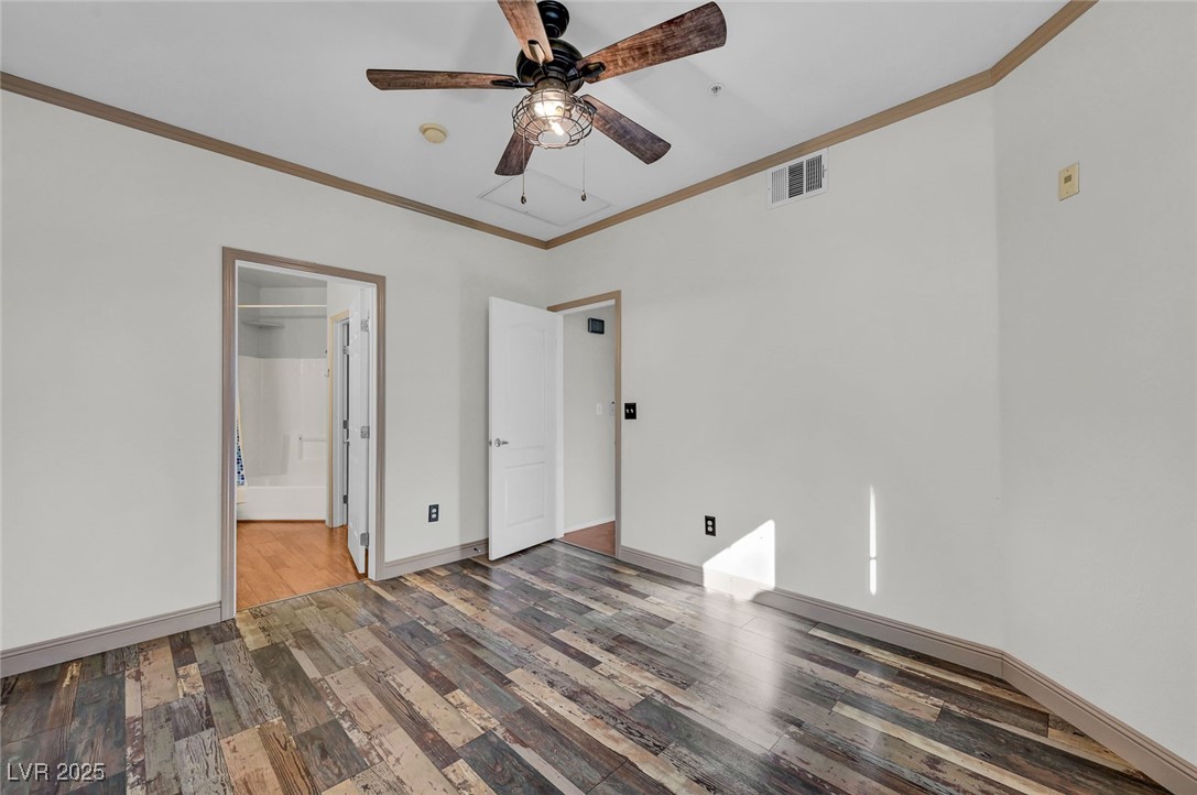 7147 South Durango Drive, Unit 304 Las Vegas, NV 89113 - Photo 20 of 27 Unfurnished bedroom featuring crown molding, wood finished floors, connected bathroom, and ceiling fan