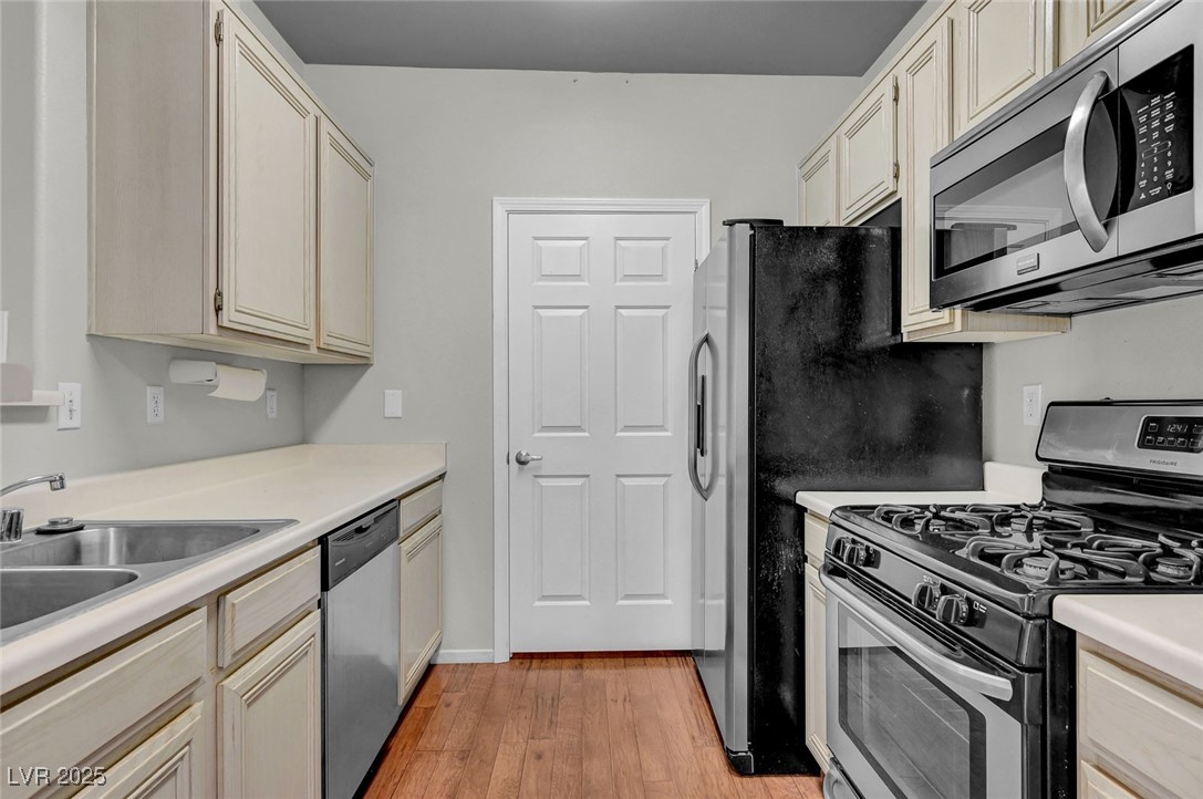 7147 South Durango Drive, Unit 304 Las Vegas, NV 89113 - Photo 5 of 27 Kitchen with appliances with stainless steel finishes, light wood finished floors, light countertops, and cream cabinetry